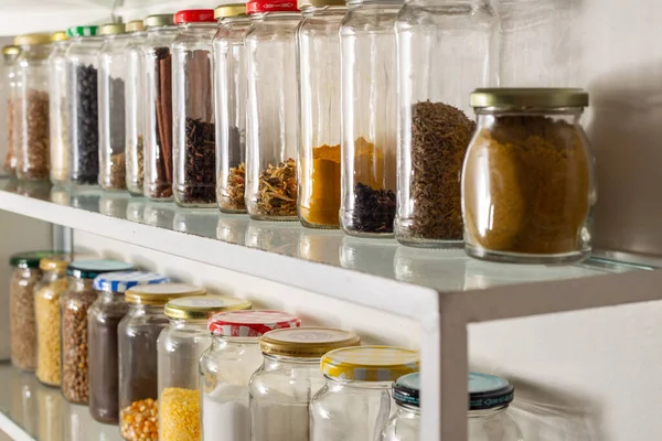 Side view of some glass containers with bulk food on a wall shelf. Reuse of glass packaging for industrialized products.