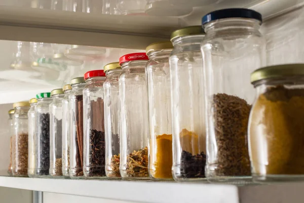 Side view of some glass containers with bulk food on a wall shelf. Reuse of glass packaging for industrialized products.