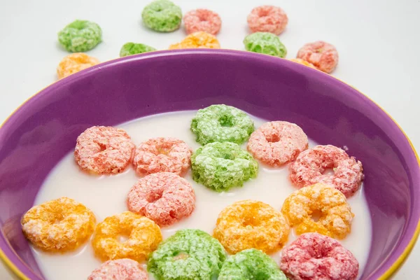 Detail of bowl with colorful breakfast cereals in milk, ready to eat and some cereals on the table.