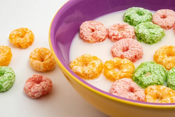 Detail of bowl with colorful breakfast cereals in milk, ready to eat and some cereals on the table.