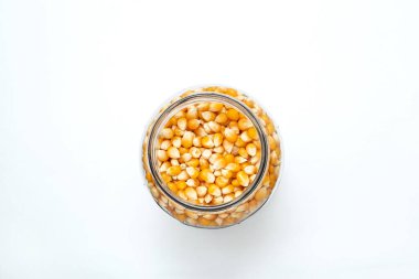 Beyaz renkli bir yüzey üzerinde cam kavanozun içinde patlamış mısır..