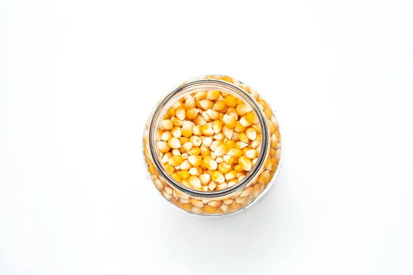 stock image Popcorn corn inside a glass jar on a white color surface.