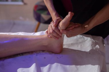 Sedyede yatan bir hastaya ayak masajı yapan bir terapist..