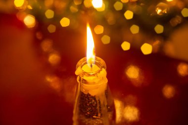 Noel süsü. Yüzeyde yanan bir mum ve çözülmüş noel ağacı ayrıntıları yansıtılıyor..