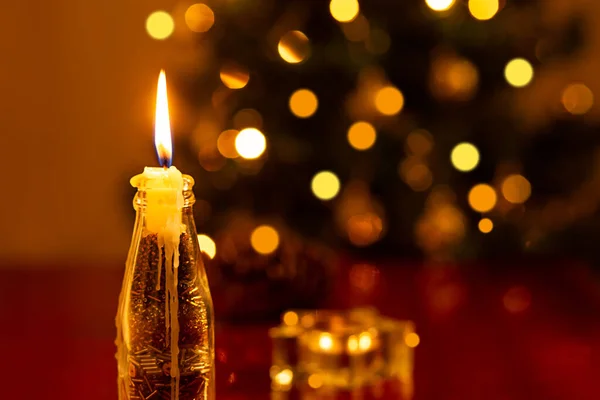 圣诞装饰 前面点着一支蜡烛 后面是一棵模糊的圣诞树 — 图库照片