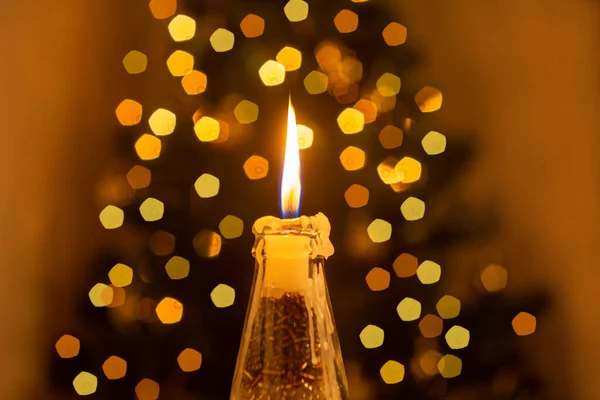 圣诞装饰 前景色点亮了一支蜡烛 背景中闪烁着圣诞树的光芒 — 图库照片