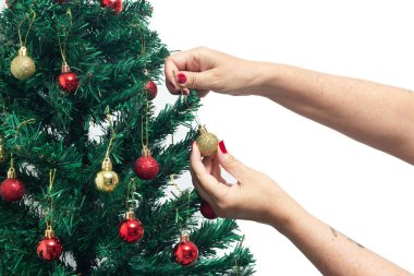 Kırmızı tırnaklı kadın elleri, kırmızı bir top tutuyor, Noel ağacını birleştiriyor..