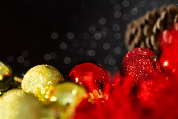 ガーランド 松のコーンと光沢のある黒の背景を持ついくつかの黄金と赤のボール クリスマスの装飾 — ストック写真