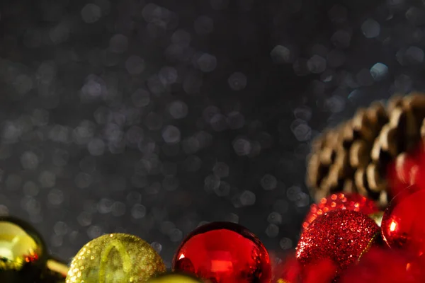 ガーランド 松のコーンと光沢のある黒の背景を持ついくつかの黄金と赤のボール クリスマスの装飾 — ストック写真