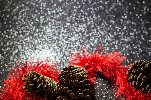 光沢のある黒い背景に松の実がある赤いガーランド — ストック写真