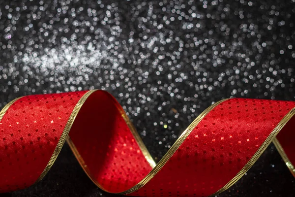 光沢のある黒い表面の上に赤 巻きリボン クリスマスの装飾 — ストック写真