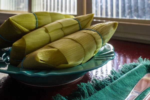 Pamonhas Pokryte Łuskami Kukurydzy Wewnątrz Płyty Przed Oknem Błyszczącej Powierzchni — Zdjęcie stockowe