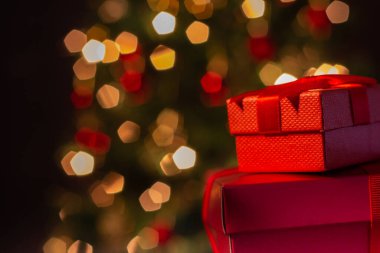 İki hediye kutusu, kırmızı, kurdeleli, arkasında Noel ağacı olan..