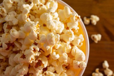 Tahta masaya serpiştirilmiş patlamış mısırla dolu bir kasenin detayları..