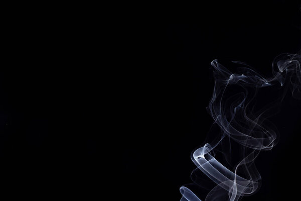 An abstract form of white smoke from incense with a black background.