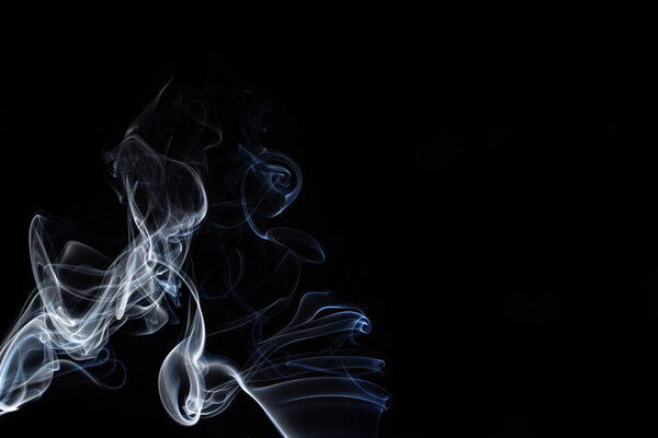 An abstract form of white smoke from incense with a black background.