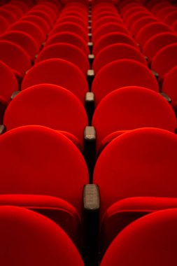 Boş bir tiyatroda birkaç sıra kırmızı koltuk..