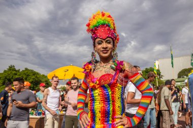 Arkaplanda bulutlu gökyüzü ve renkli kostümlü bir LGBT çalışanı. Fotoğraf Goiania şehrindeki LGBTQIA Onur Yürüyüşü sırasında çekildi..