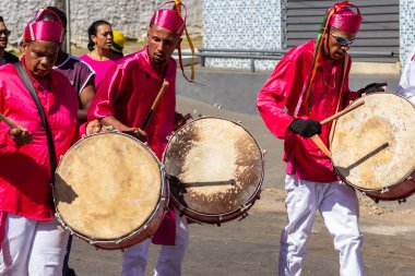 Kırmızı elbiseli, dans eden ve Congadas boyunca perküsyon enstrümanları çalan hayranlar, Angola ve Kongo 'dan gelen kabile geleneklerinin öğeleriyle dolu bir dini festival..
