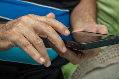 Cep telefonu kullanan yaşlı bir adamın ellerinin ayrıntıları..
