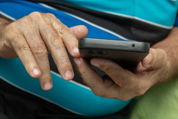 关于使用手机的老年男子双手的细节 免版税图库图片