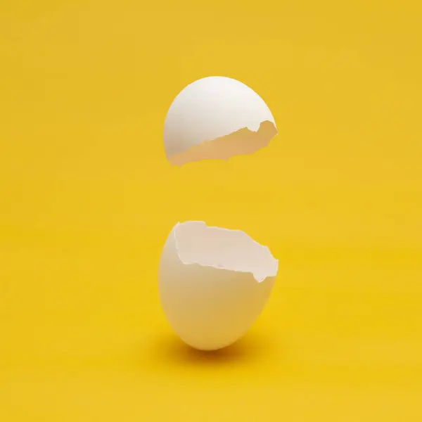 破碎的白色蛋的壳 有黄色的背景 免版税图库照片