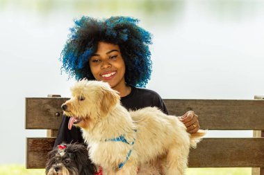 Parktaki bankta iki köpeği olan genç bir kadın..