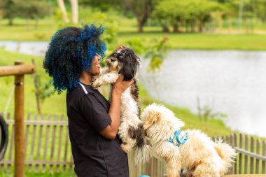 Kollarında bir köpek ve yanında bir köpek tutan genç bir kadın..