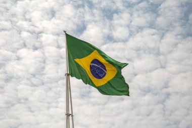 Bulutlu bir günde rüzgarda dalgalanan bir Brezilya Bayrağı.