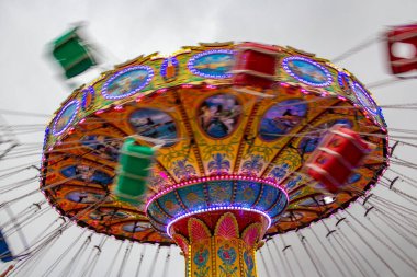 Renkli, dev bir döner oyuncak, hızla dönüyor, zincirlerle bağlanmış sandalyelerle, birkaç kişiyle, bir lunaparkta. Fotoğraf aşağıdan yukarıya düşük kamera hızında çekildi.