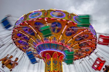 Bir lunaparkta, zincirlerle bağlı sandalyelerle dönen dev bir dönme dolap. Fotoğraf aşağıdan yukarıya düşük kamera hızında çekildi.