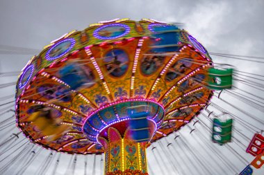Bir lunaparkta, zincirlerle bağlı sandalyelerle dönen dev bir dönme dolap. Fotoğraf aşağıdan yukarıya düşük kamera hızında çekildi.