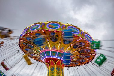 Bir lunaparkta, zincirlerle bağlı sandalyelerle dönen dev bir dönme dolap. Fotoğraf aşağıdan yukarıya düşük kamera hızında çekildi.