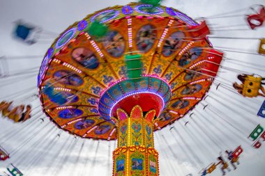 Bulutlu bir günde eğlence parkında birkaç kişiyle hareket halindeki bir rotasyon. Fotoğraf aşağıdan yukarıya doğru çekilmiş..
