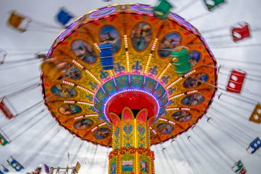 Bulutlu bir günde eğlence parkında birkaç kişiyle hareket halindeki bir rotasyon. Fotoğraf aşağıdan yukarıya doğru çekilmiş..