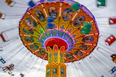 Bulutlu bir günde eğlence parkında birkaç kişiyle hareket halindeki bir rotasyon. Fotoğraf aşağıdan yukarıya doğru çekilmiş..