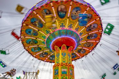 Bulutlu bir günde eğlence parkında birkaç kişiyle hareket halindeki bir rotasyon. Fotoğraf aşağıdan yukarıya doğru çekilmiş..