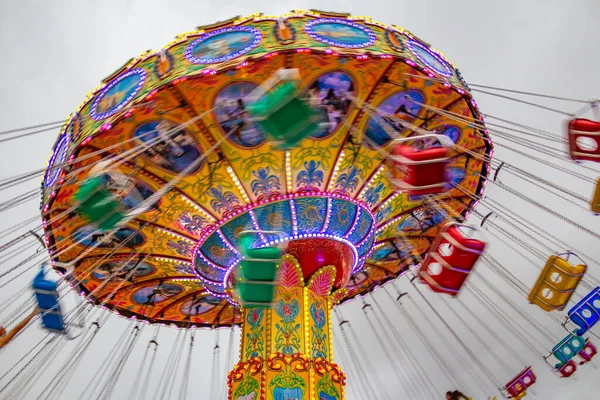 Renkli, dev bir döner oyuncak, hızla dönüyor, zincirlerle bağlanmış sandalyelerle, birkaç kişiyle, bir lunaparkta. Fotoğraf aşağıdan yukarıya düşük kamera hızında çekildi.