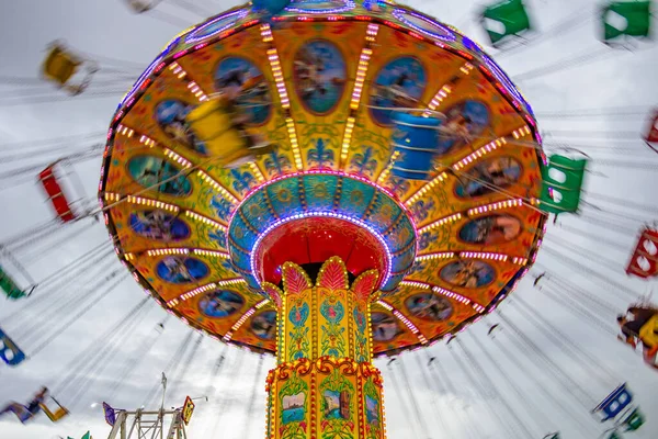 Bulutlu bir günde eğlence parkında birkaç kişiyle hareket halindeki bir rotasyon. Fotoğraf aşağıdan yukarıya doğru çekilmiş..