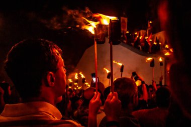 Fogareu alayı. Goias 'ta dini bir törende bir inananın sırtı ve birkaç kişi daha tunik giymiş ve elinde bir ateş meşalesi tutuyordu..