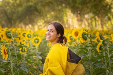 Bir ayçiçeği çiftliğinin ortasında gülümseyen bir arı yetiştiricisi..
