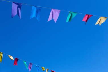  Arka planda mavi gökyüzü asılı renkli bayraklı iki tel. Metin için boşluk ile.