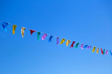 Arka planda mavi gökyüzü olan çeşitli renkli bayraklar asılı. Yazmak için boşluk ile.