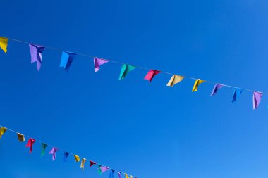  Arka planda mavi gökyüzü asılı renkli bayraklı iki tel. Metin için boşluk ile.