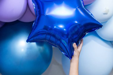 Bir çocuğun elinde yıldız şeklinde mavi bir balon yakalama ayrıntıları.