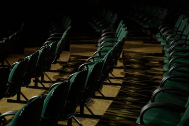 Oditoryumda birkaç sıra yeşil sandalye arkadan çekilmiş..