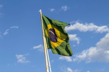 Brezilya bayrağı, bayrak direğinde dalgalanan gökyüzü ve arka planda bulutlar..