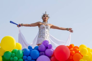 An LGBT person, dressed in white with a float decorated with balloons, dancing, at the 2024 LGBT Pride Parade in the city of Goiania in Brazil. clipart