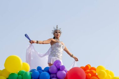 Brezilya 'daki Goiania şehrinde düzenlenen 2024 LGBT Onur Yürüyüşü' nde balonlarla süslenmiş, beyaz bir şamandırayla dans eden bir LGBT çalışanı..