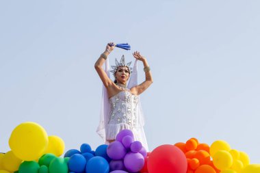 An LGBT person, dressed in white with a float decorated with balloons, dancing, at the 2024 LGBT Pride Parade in the city of Goiania in Brazil. clipart